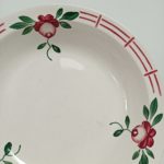 Détail du décor fleuri et de la frise rose bordeaux du plat Castille