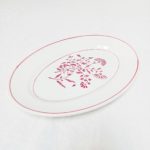 Plat ovale ancien fleuri présenté sur une table vintage