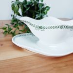 Détail décor feuillage et nœud vert sur saucière ancienne terre de fer.